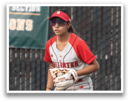 A girl in a red and white uniform is standing on a baseball field. Description generated by AI