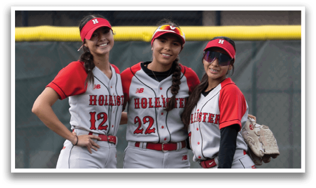 Three women standing on a baseball field. Description generated by AI
