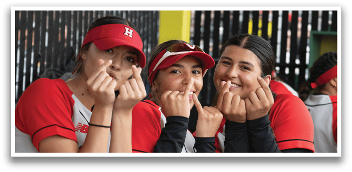Three female baseball players wearing red and white uniforms. Description generated by AI