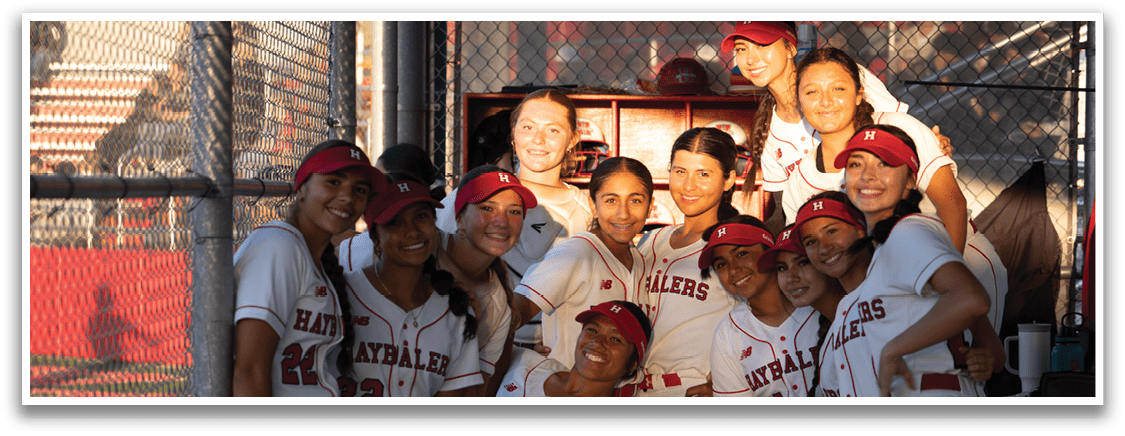 A group of girls wearing baseball uniforms. Description generated by AI