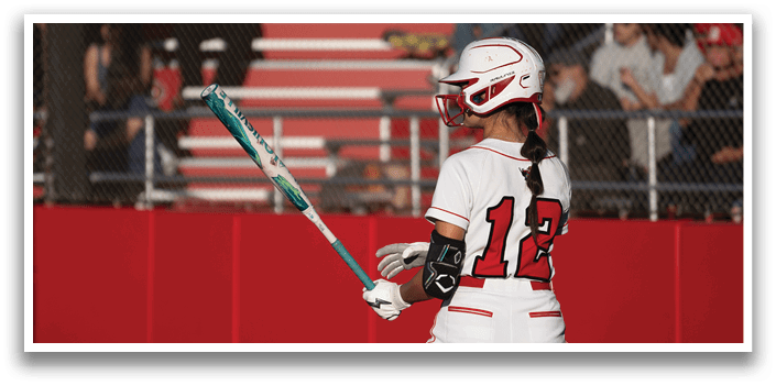 A girl is holding a bat and standing on a field. Description generated by AI