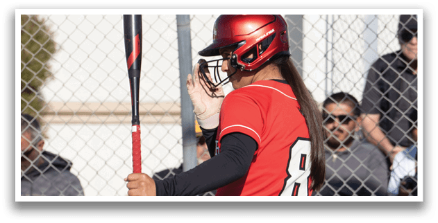 A woman wearing a red shirt and black pants holding a bat. Description generated by AI