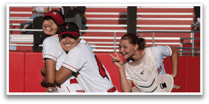 Three girls hugging each other on a baseball field. Description generated by AI