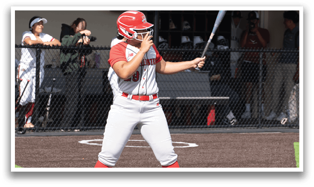 A woman in a red and white uniform is swinging a bat. Description generated by AI