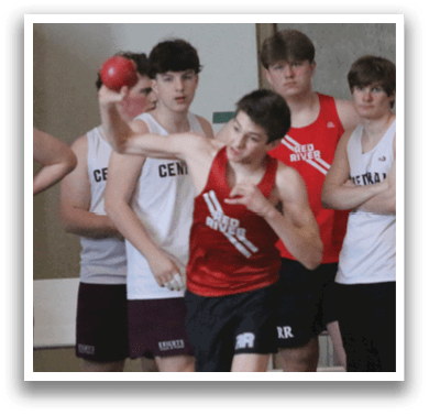 A group of men are standing in a gym, wearing red shirts and black shorts. They are lined up, possibly waiting for their turn to compete in a race or event. AI generated content
