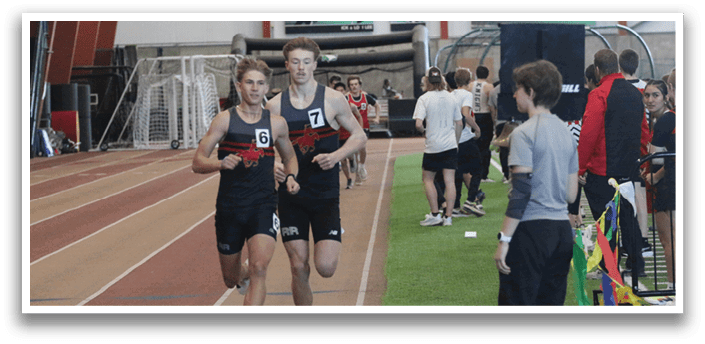 Two men are running on a track, one in front of the other. They are wearing black and red outfits. There are several other people in the background, some of whom are standing and others are running. A banner can be seen in the background, and a clock is visible on the wall. AI generated content