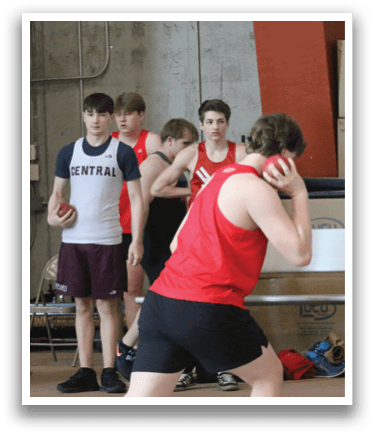 A group of people are standing in a gym, watching a man perform a shot put. AI generated content