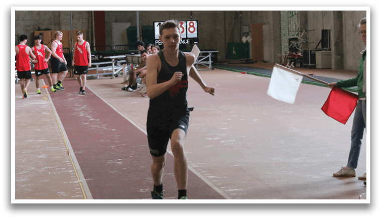 A man is running on a track while wearing a black shirt and shorts. He is running in front of a group of people, including a woman holding a red flag. The scene appears to be a competition or practice session. AI generated content