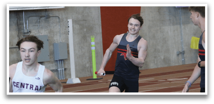 Two men are running on a track, one in front of the other. The man in front is wearing a white shirt and black shorts. AI generated content