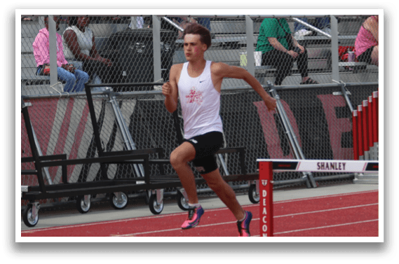 A man running in front of a red and white barrier. Description generated by AI