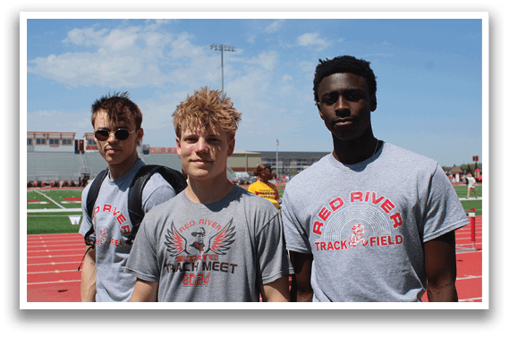 Three young men wearing grey shirts and sunglasses. Description generated by AI
