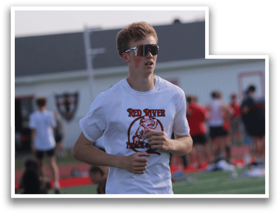 A man wearing a white shirt and black shorts is running on a field. Description generated by AI