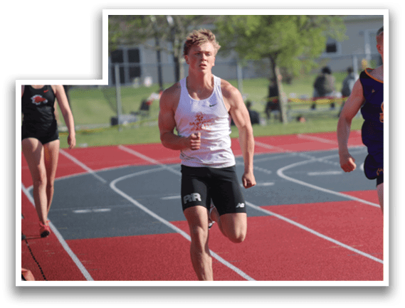 A man running on a track with a purple shirt on. Description generated by AI