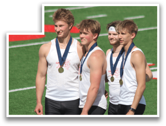 Four men standing on a field, wearing black shorts and white shirts. Description generated by AI