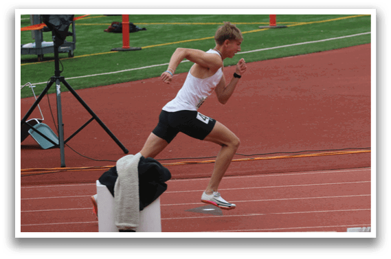 A man running on a track with a white shirt and black shorts. Description generated by AI