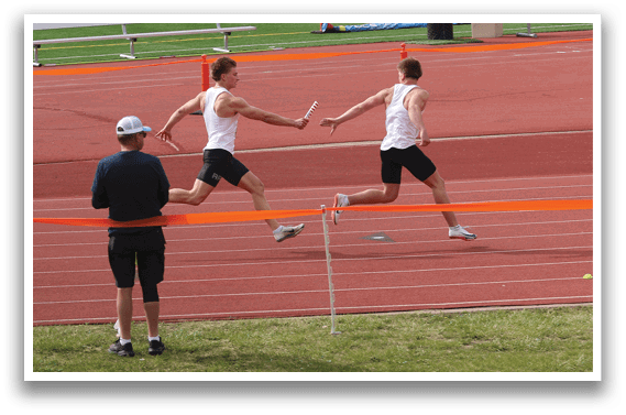 A man running on a track with a man in a blue shirt watching. Description generated by AI