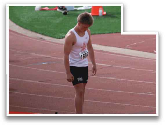 A man wearing a white shirt and black shorts is standing on a track. Description generated by AI