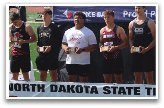 A group of young men stand on a track field, with one of them holding a trophy. Description generated by AI