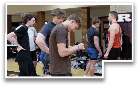 A group of men standing in a gym. Description generated by AI