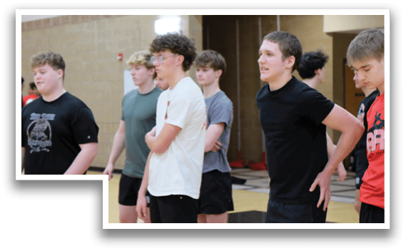 A group of boys wearing black shirts and shorts are standing in a line. Description generated by AI