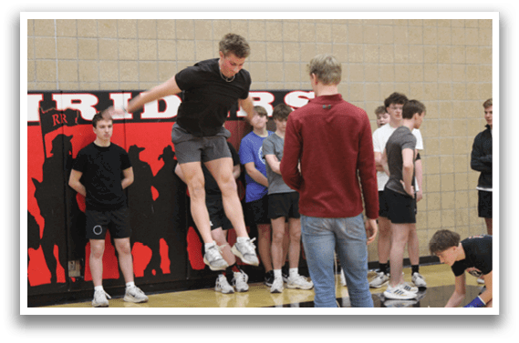 A man is jumping in the air in front of a group of people. Description generated by AI