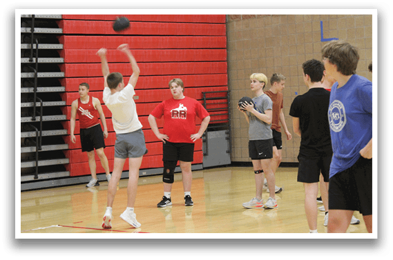 A group of people playing basketball in a gym. Description generated by AI