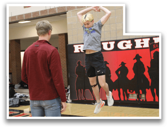 A boy is jumping in the air in front of a brick wall with a red and black sign. Description generated by AI