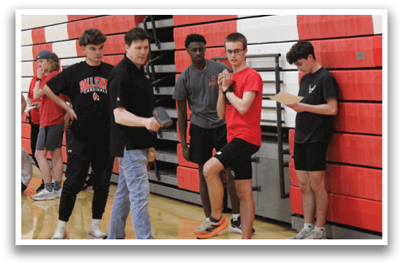 A group of people standing in a gym. Description generated by AI
