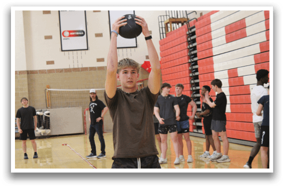 A man holding a black ball in a gym. Description generated by AI
