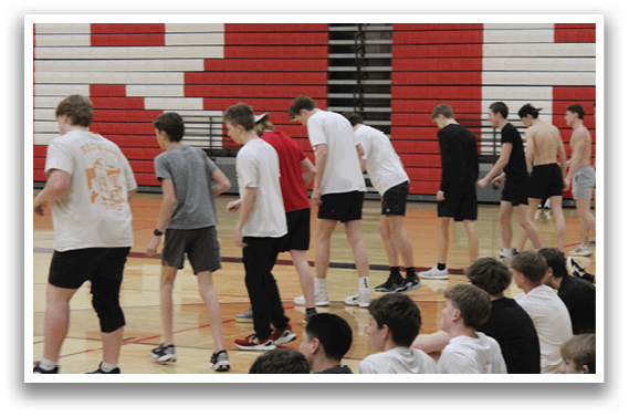 A group of men are standing on a basketball court. Description generated by AI