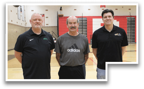 Three men standing on a basketball court. Description generated by AI