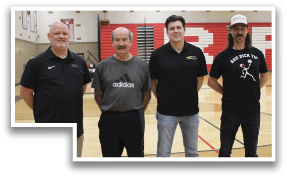 Four men standing on a basketball court. Description generated by AI