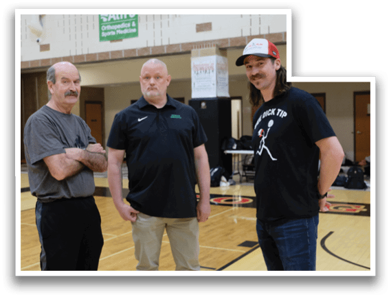 Three men standing on a basketball court. Description generated by AI