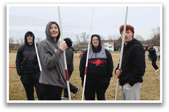 Four people standing in a field holding white poles. Description generated by AI
