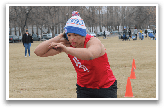 A woman wearing a red shirt and a blue hat is bending over. Description generated by AI