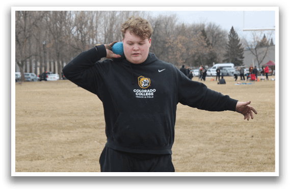 A man wearing a black and gold shirt is holding a blue frisbee. Description generated by AI