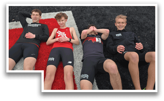 Four men are sitting on the ground. Description generated by AI