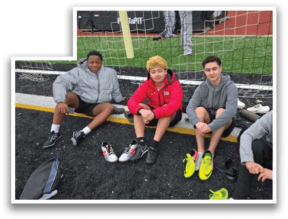 Four young men sitting on the ground, wearing sneakers. Description generated by AI