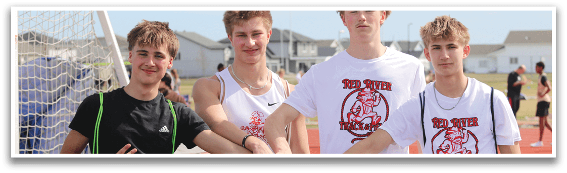 Four young men standing on a field, posing for a picture. Description generated by AI