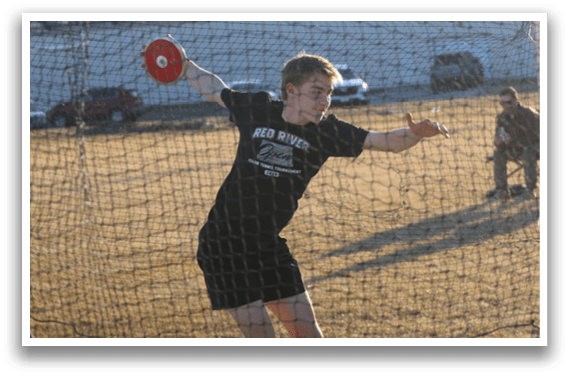 A man wearing a black shirt and red shoes is throwing a weight. Description generated by AI