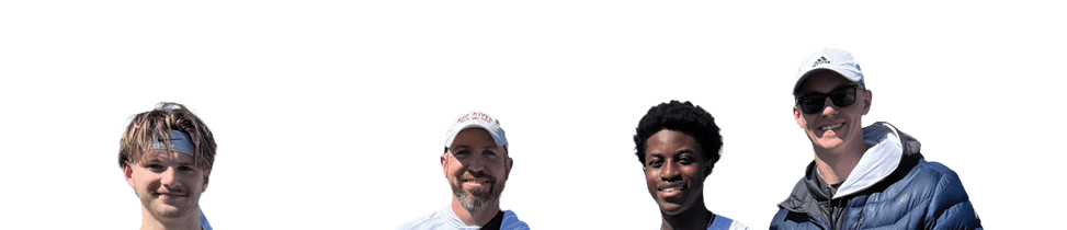Four people standing on a field. Description generated by AI