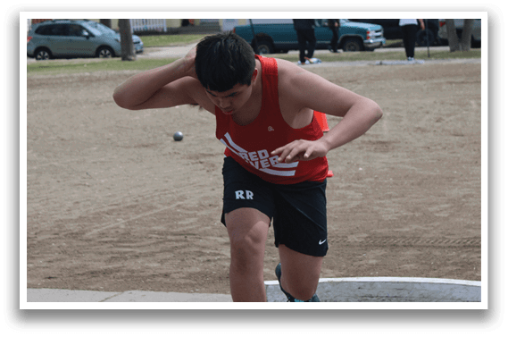A man wearing a red shirt and black shorts is throwing a frisbee. Description generated by AI