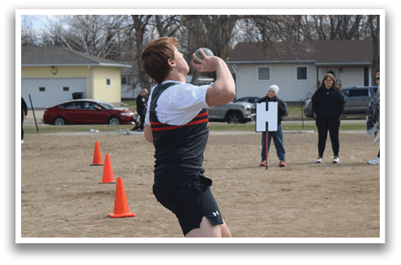 A man wearing a black and red shirt is catching a frisbee. Description generated by AI