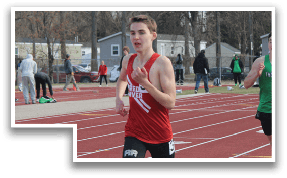 A man wearing a red tank top is running on a track. Description generated by AI