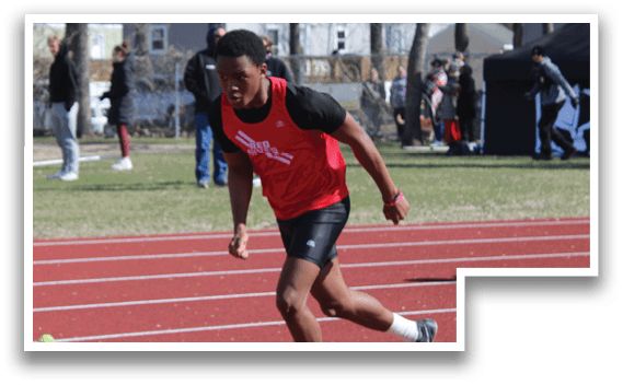 A man running on a track with a red shirt and black shorts. Description generated by AI