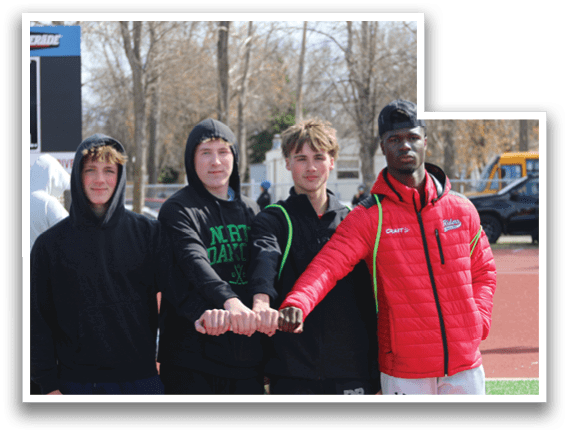 Four young men standing on a track. Description generated by AI