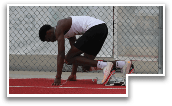 A man is bending over on a track. Description generated by AI