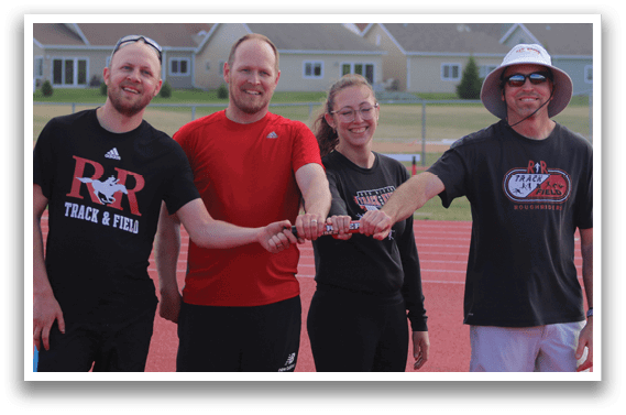 Four people standing on a track. Description generated by AI