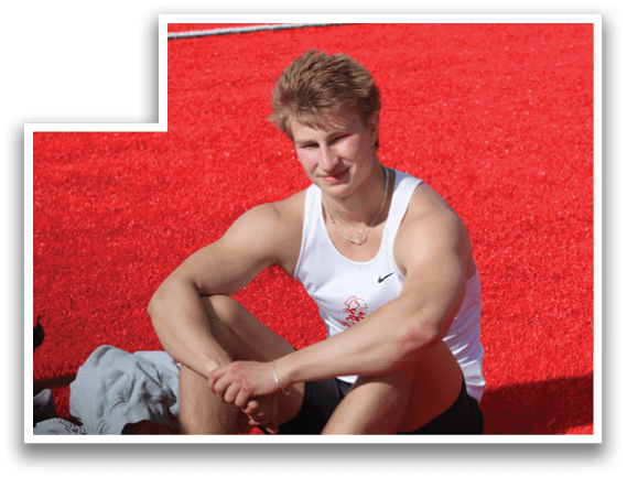 A man wearing a white tank top and black shorts sitting on the ground. Description generated by AI