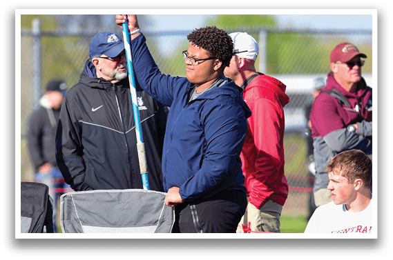 A man holding a pole in front of a crowd of people. Description generated by AI